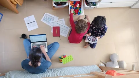 Young mother working at home while taking care of her sons Vídeos de archivo 270483643