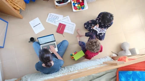 Young mother working at home while taking care of her sons Vídeos de archivo 270483644