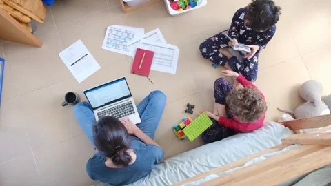 Young mother working at home while taking care of her sons Vídeos de archivo 270483651
