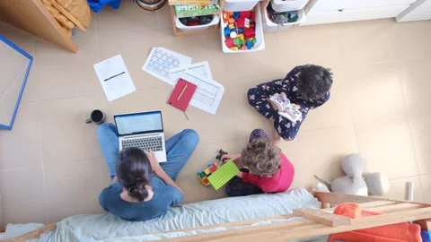 Young mother working at home while taking care of her sons Vídeos de archivo 270483655
