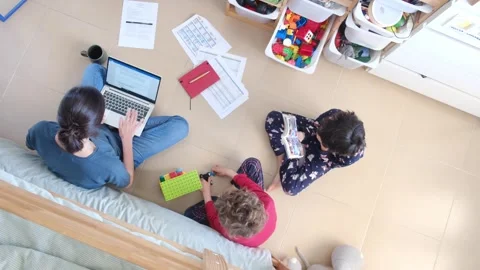 Young mother working at home while taking care of her sons Vídeos de archivo 270483664