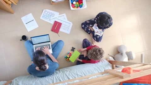 Young mother working at home while taking care of her sons Vídeos de archivo 270483671