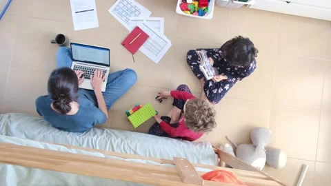Young mother working at home while taking care of her sons Vídeos de archivo 270483684