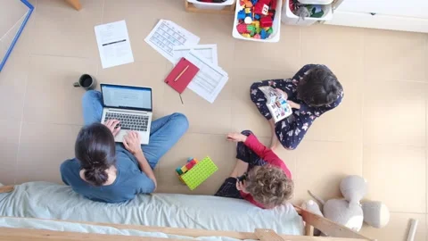 Young mother working at home while taking care of her sons Vídeos de archivo 270483703