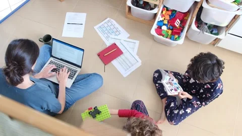 Young mother working at home while taking care of her sons Vídeos de archivo 270483717