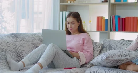 Young mother working on laptop with two daughter on sofa Stock Footage 138337399