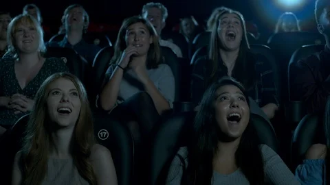 Young movie theatre audience burst into laughter while watching a comedy film. Stock Footage