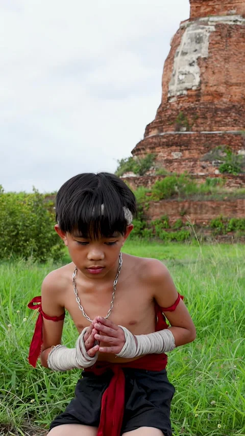 Young Muay Thai Fighter Kneeling and Praying at Ancient Temple Ruins Stock Footage 339823349