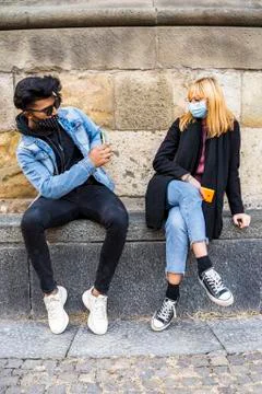 Young multi-ethnic couple exchanges information on their mobile phones wearin Stock Photos