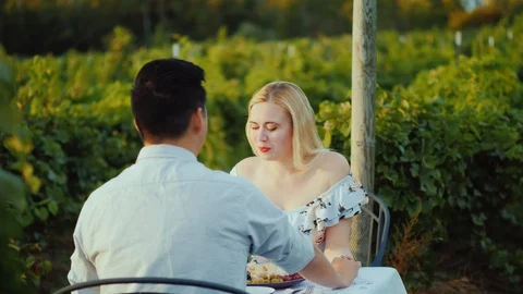 A young multi-ethnic couple is having dinner with glasses of wine in a Stock Footage 98298415
