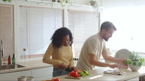 Young multi-ethnic couple in the kitchen while cooking and cleaning. Stock Footage 169414911