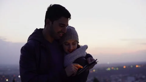 Young multi-ethnic couple using tablet outdoors in winter after sunset Stock Footage 133280551