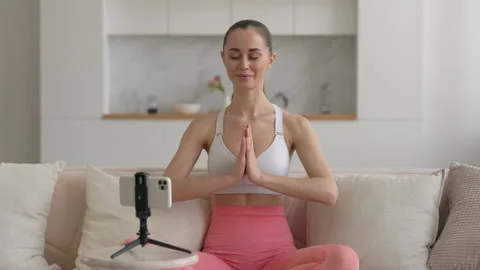 Young multi ethnic yoga coach, practicing breathing yoga pranayama on living Stock Footage 148284966