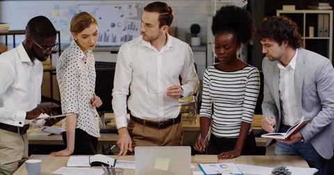 Young multi-ethnical business team working on a project and their boss giving Stock Footage 82444634