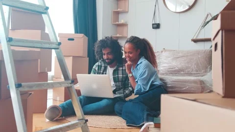 Young multicultural couple man and woman with laptop after moving to new house Stock Footage 217443775