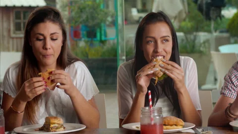 Young multicultural group of friends laughing and sharing a meal/eating around a Stock-Footage 199633540