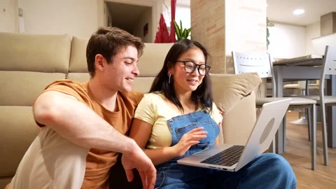 Young multiethnic couple browsing laptop at home Stock Footage 305236949
