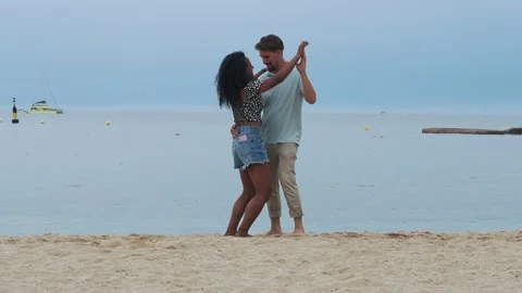 Young multiethnic couple happily dancing on the beach during sunset Stock Footage 218978839