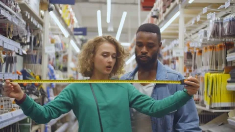 Young multiethnic couple in hardware store using measuring tape Stock Footage 136315664
