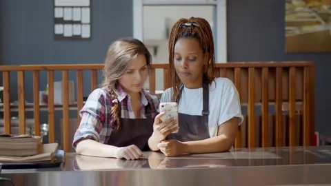 Young multiethnic owners of small modern coffee house using smartphone for work. Stock Footage 134547311