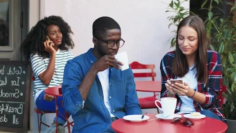 Young multinational couple sitting on terrace of cafe and talking drinking Stock Footage 151848737