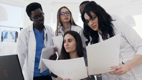 Young multinational medical doctors having meeting, using laptop and paper Stock Footage 105975628