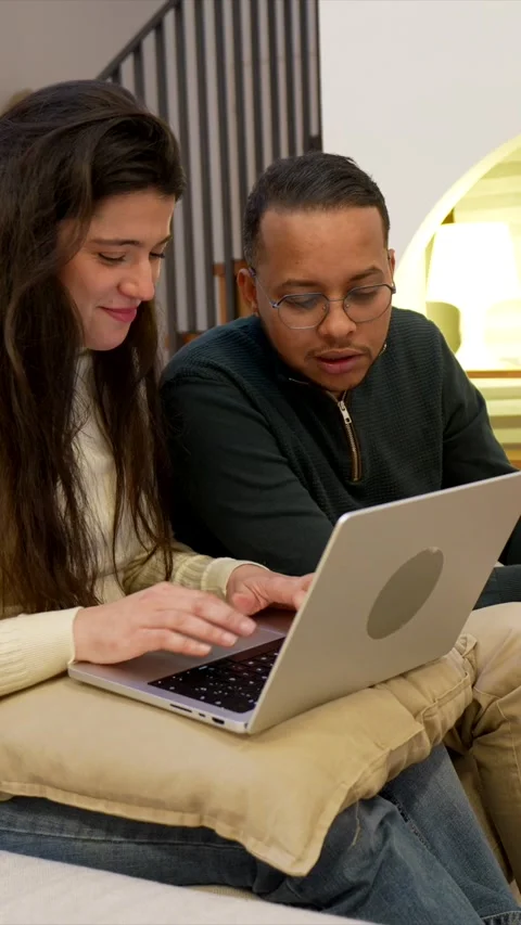 Young multiracial couple using laptop computer together at home Stock Footage 334134252