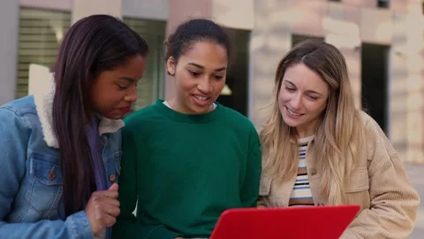 Young multiracial female students working together on laptop sitting outdoors Stock Footage 228499587