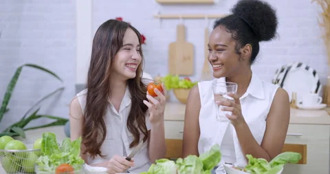 Young multiracial friends sitting kitchen table laughing together while drinking Stock Footage 320447713