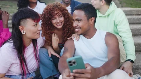 Young multiracial group of friends using mobile smartphone sitting outside of Video stock 335263345