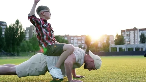 Young muscular father doing push-ups with his little son on his back. Stock Footage 282013138
