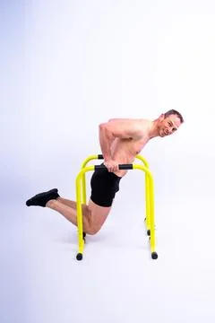 Young muscular man doing parallel bar exercises in dark white red studio with Stock Photos