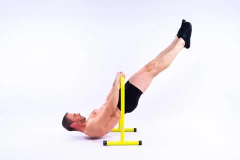 Young muscular man doing parallel bar exercises in dark white red studio with Stock Photos