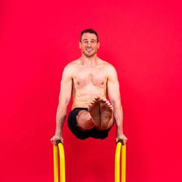 Young muscular man doing parallel bar exercises in dark white red studio with Stock Photos