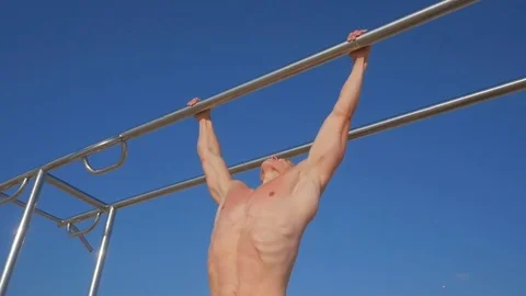 Young muscular man doing pull-ups on horizontal bar against blue background Video stock 84041837