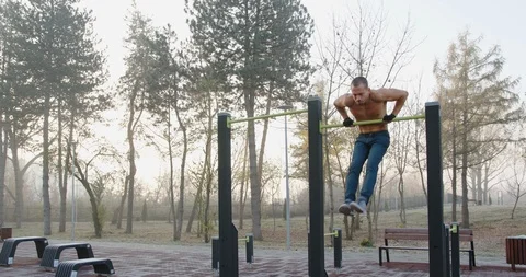 Young muscular man doing pull ups over the bar in fitness park Stock Footage 121715277