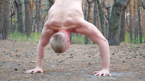 Young muscular man doing push upsin handstand at forest. Hardy and strong guy Video stock 300083617