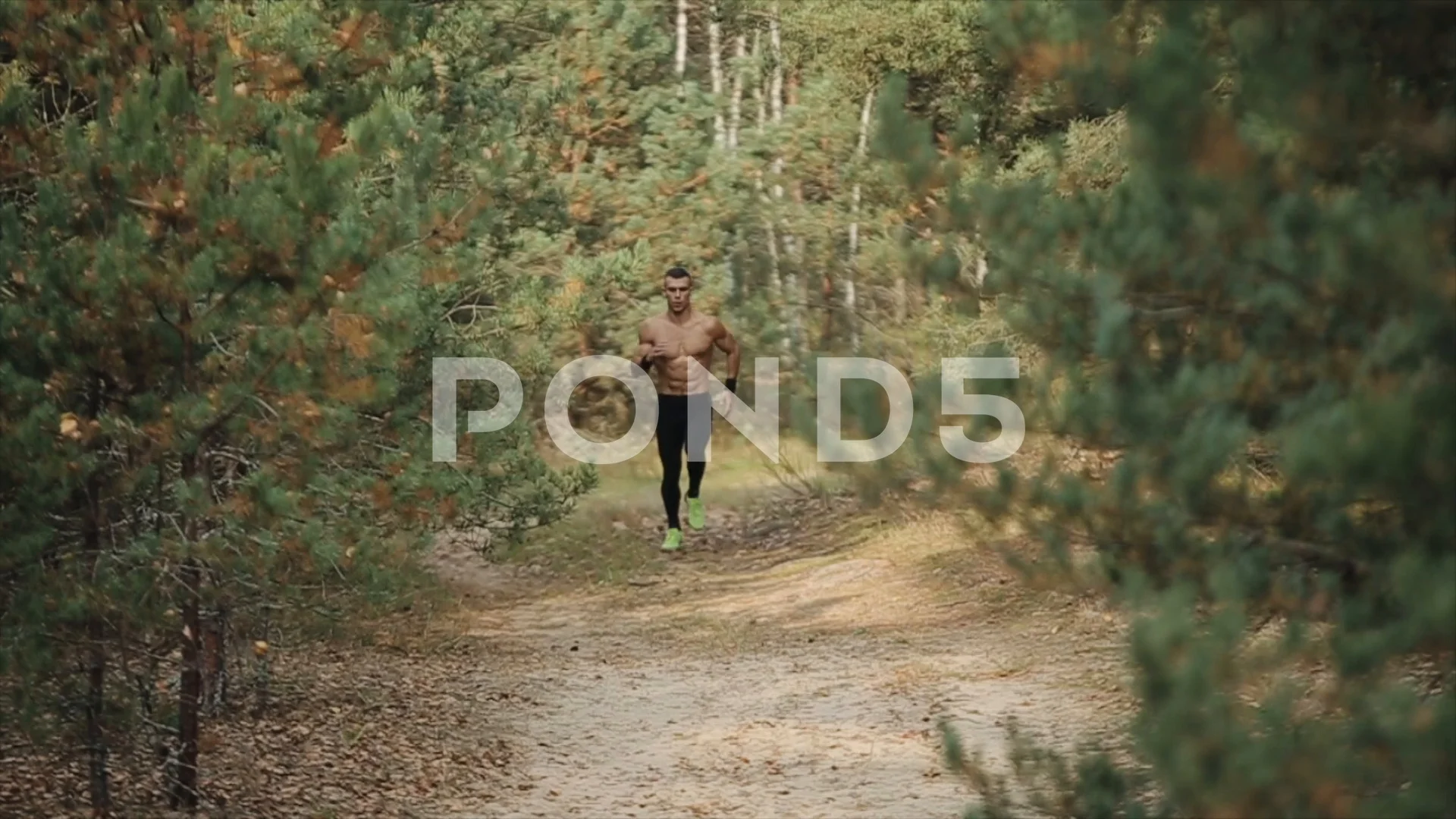 Young muscular man running with naked torso runs along trail at early autumn