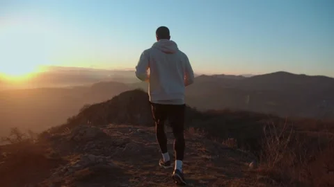 Young muscular man running through the beautiful landscape at sunset . Stock Footage 239555997