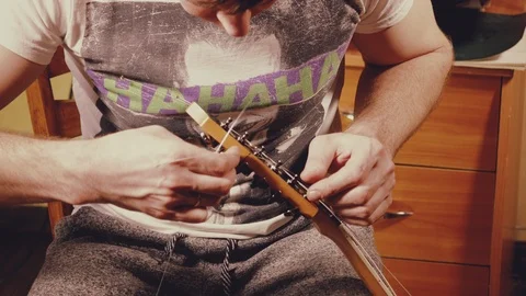 A young musician changes the strings on the guitar Stock Footage 103422680