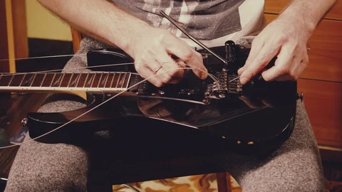 A young musician changes the strings on the guitar Stock Footage 103422712