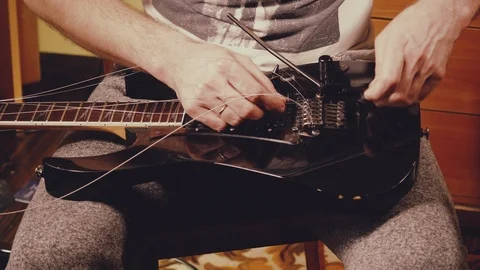A young musician changes the strings on the guitar Stock Footage 103422742