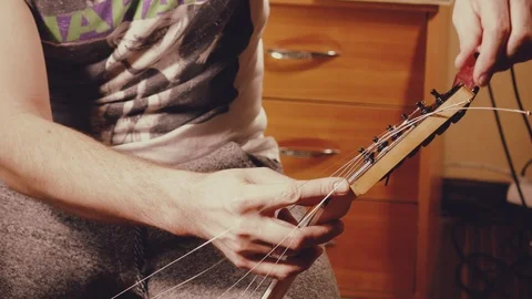 A young musician changes the strings on the guitar Stock Footage 103422768