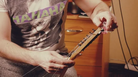 A young musician changes the strings on the guitar Stock Footage 103422790