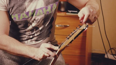 A young musician changes the strings on the guitar Stock Footage 103422823