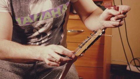 A young musician changes the strings on the guitar Stock Footage 103422848