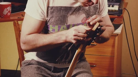 A young musician changes the strings on the guitar Stock Footage 103422965