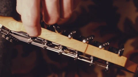 A young musician changes the strings on the guitar Stock Footage 103423100