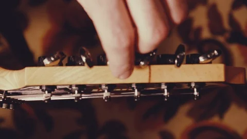 A young musician changes the strings on the guitar Stock Footage 103423145