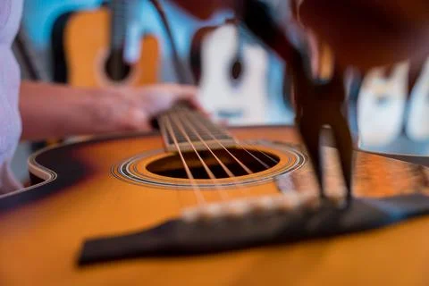 Young musician changing strings on a classical guitar in a guitar shop Stock Photos